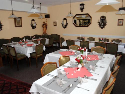 une salle à manger avec des tables et des chaises blanches ainsi que des serviettes rouges dans l'établissement Pension Waldesruh, à Welschneudorf