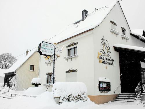 un edificio cubierto de nieve con un cartel. en Pension Waldesruh en Welschneudorf
