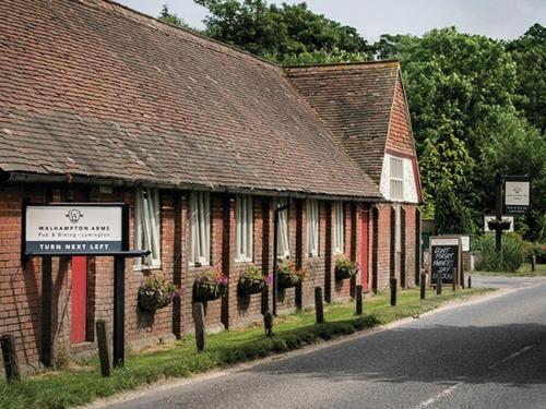 un edificio de ladrillo con macetas al lado de una calle en The Walhampton Arms, en Lymington