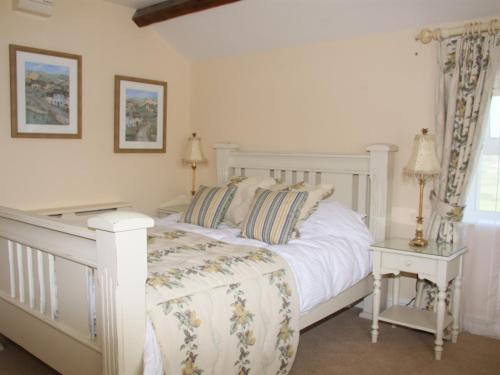 a white bedroom with a white bed and two tables at Wall Hill Farm in Northwich