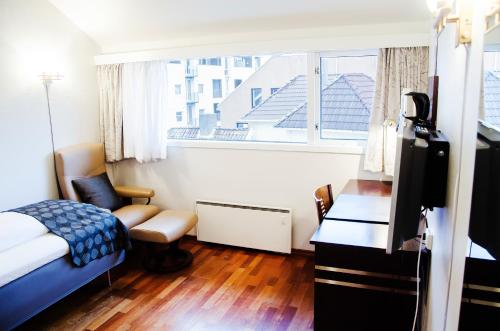 a bedroom with a bed and a desk and a window at Havly Hotell in Stavanger