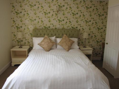 a bedroom with a white bed with floral wallpaper at Wellington Inn in Harrogate
