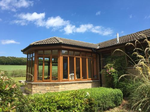 a house with a conservatory with glass at Wester Muirhouse in Linlithgow