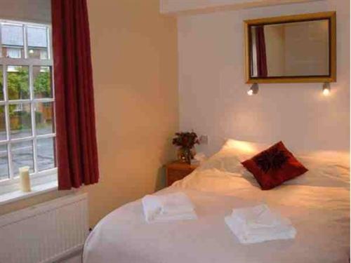 a bedroom with a white bed with a window at The Wheatsheaf Inn in Cuckfield