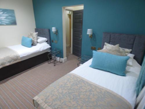 a bedroom with two beds with blue walls at Wheldale Hotel-Bed and Breakfast in Castleford