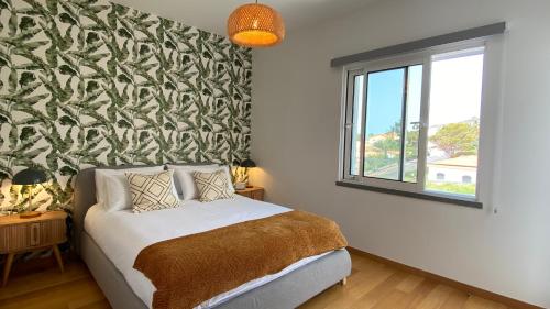 a bedroom with a bed with a green and white patterned wall at Madeira Mero Apartment in Caniço