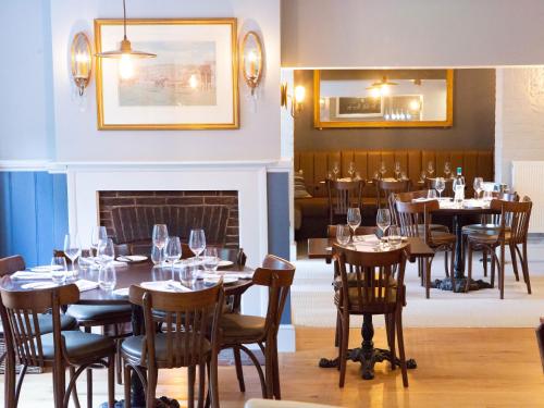a dining room with tables and chairs and a fireplace at The White Horse Inn in Pulborough