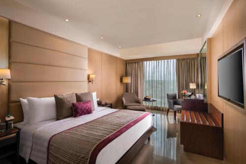 a hotel room with a bed and a flat screen tv at Jaypee Siddharth in New Delhi