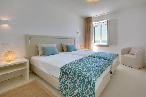 a bedroom with a bed and a chair and a window at Casa da Bandeira -Perfect Location-Beach front- Rooftop Pool by DreamvillasAlbufeira in Albufeira