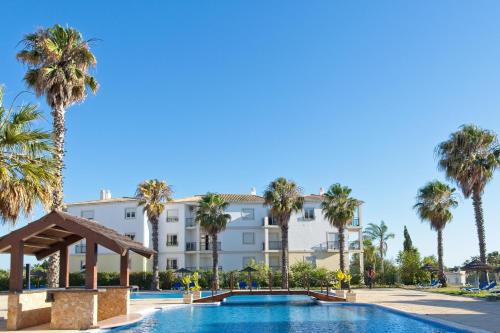 um hotel com piscina e palmeiras em TURIM Estrela do Vau Hotel em Portimão