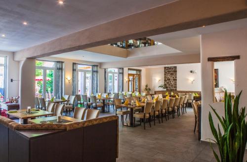 a restaurant with tables and chairs and windows at Landgasthof Winzerscheune in Valwig