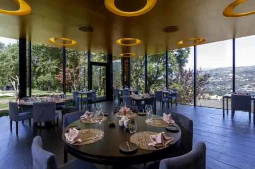 a restaurant with tables and chairs and large windows at Douro Palace Hotel Resort & SPA in Baião