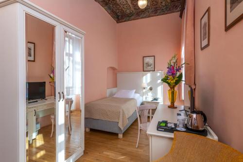 Habitación pequeña con cama y escritorio con mesa. en Hotel Cerny Slon, en Praga