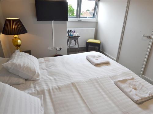 ein Schlafzimmer mit einem weißen Bett und Handtüchern darauf in der Unterkunft Woodberry Inn in Bridgnorth