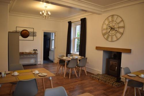 a dining room with a fireplace and a clock on the wall at Woodlyn Guest House in Gatehouse of Fleet