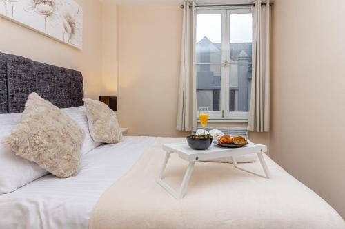 a white bed with a tray of fruit and a table on it at Guest Homes - Trinity Flat in Worcester