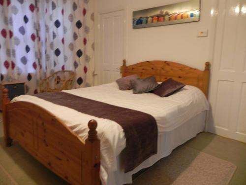 una camera con letto in legno e lenzuola bianche di The Weston Super Mare Guest House a Weston-super-Mare