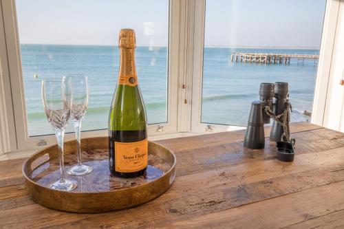 a bottle of wine and two glasses on a table at Water's Edge Apartment in Totland