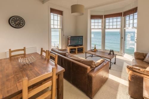 a living room with a couch and a table at Water's Edge Apartment in Totland
