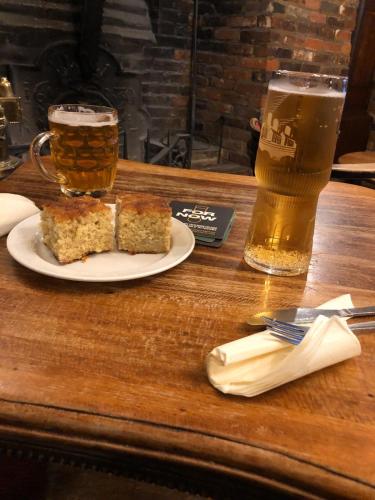 a table with a plate of cake and a glass of beer at Ye Olde White Harte Hotel in Burnham on Crouch