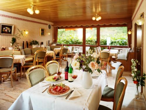 a dining room with tables and chairs with flowers on them at Pension zur Mühle in Veldenz