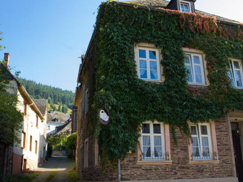 a building covered in ivy with a clock on it at Hotel zur Post - Burg an der Mosel in Burg an der Mosel
