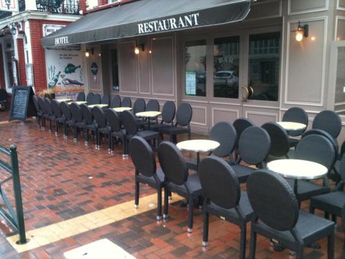 uma fila de mesas e cadeiras em frente a um restaurante em Hôtel La Champagne Ardenne Cabourg em Cabourg