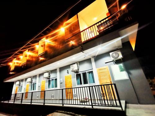 a building with yellow doors and a balcony at night at ลิตเติ้ล ฮิลล์ สัตหีบ รีสอร์ท ( Little Hill Sattahip Resort ) in Sattahip