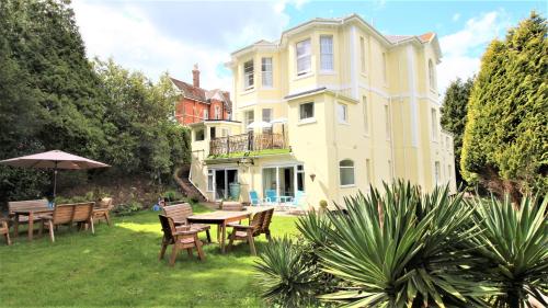 uma casa grande com uma mesa e cadeiras no quintal em Chelston Dene Holiday Apartments em Torquay