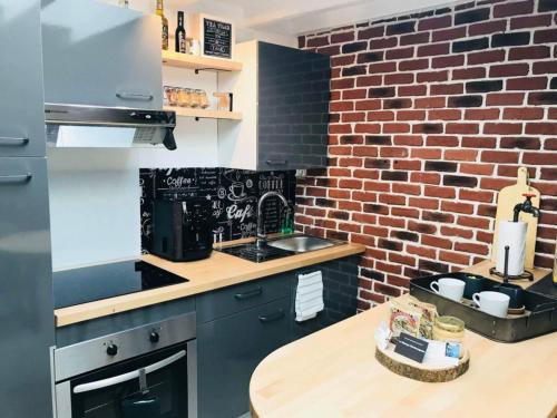 une cuisine avec un mur en briques et une table en bois dans l'établissement La Fabrique - Les Loges Normandes, à Cherbourg en Cotentin