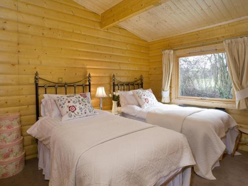2 camas en una cabaña de madera con ventana en Cherbridge Lodges - Riverside lodges, short lets (business or holidays) en Oxford