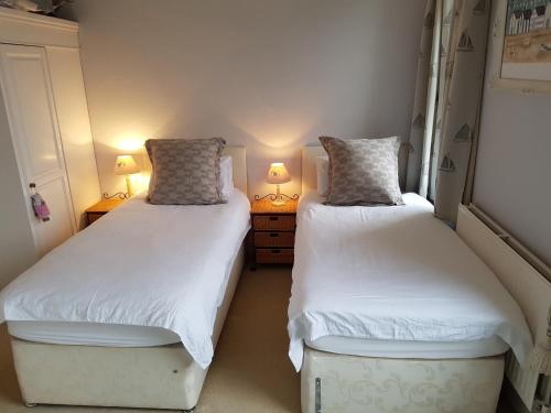 two beds in a small room with two lamps at Cherry End Bed and Breakfast in Chichester