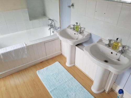 a white bathroom with a sink and a bath tub at Cherry End Bed and Breakfast in Chichester