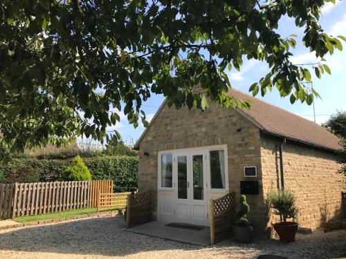 een klein bakstenen gebouw met een witte deur bij Cherry Tree Cottage in idyllic Cotswold village in Chipping Norton