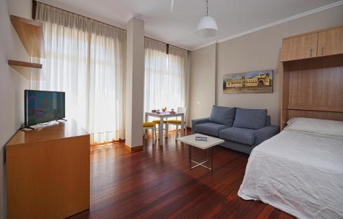ein Schlafzimmer mit einem Bett, einer Couch und einem Tisch in der Unterkunft Hotel Apartamentos Dabarca in Pontevedra