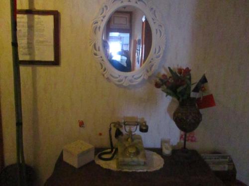 ニースにあるシェ ブリジット ゲストハウスの鏡と花瓶がテーブルに飾られた部屋