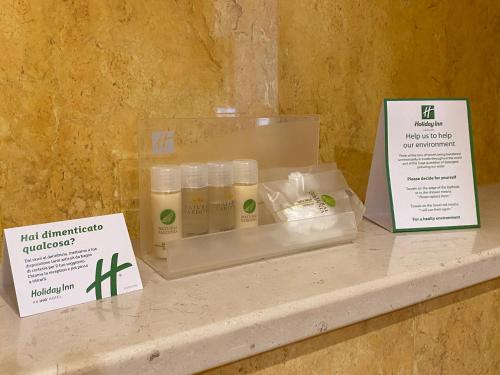 a set of four bottles of hair oil sitting on a shelf at Holiday Inn Cagliari by IHG in Cagliari