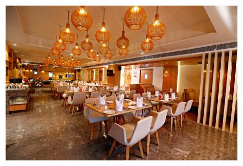a dining room with tables and chairs and chandeliers at Best Western Plus Tejvivaan in Visakhapatnam
