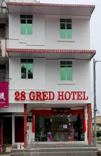 a white building with a red and green sign at 28 Gred Hotel in Bukit Mertajam