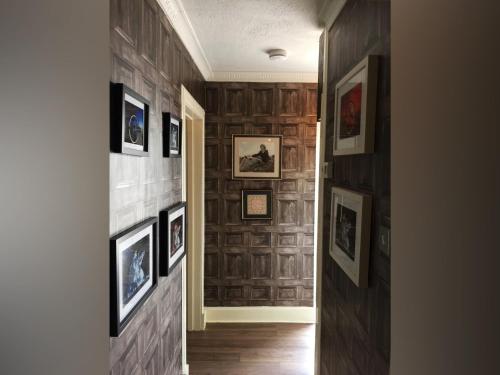 a hallway with framed pictures on a wall at The Clacks Rustic Abode in Tillicoultry