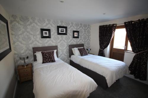 1 dormitorio con 2 camas y ventana en The Clothiers Arms en Stroud