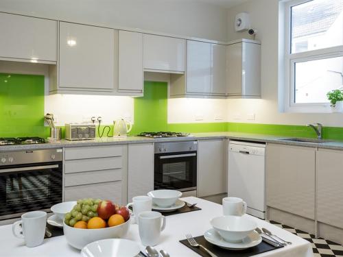 a kitchen with white cabinets and a bowl of fruit on a table at Blue Star House in Portsmouth