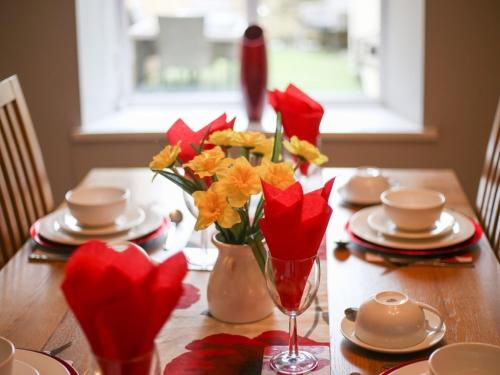 Ein Holztisch mit roten und gelben Blumen in einer Vase in der Unterkunft Colliery Cottage in Durham