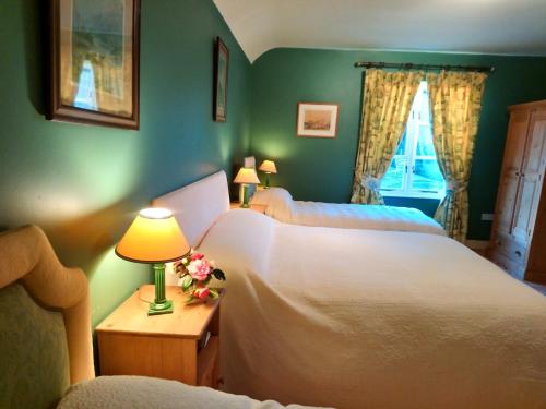 a bedroom with two beds and a table with a lamp at Kilmokea Coach House in New Ross