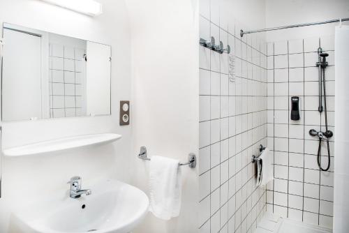 a white bathroom with a sink and a shower at Hôtel Métropole in Lourdes