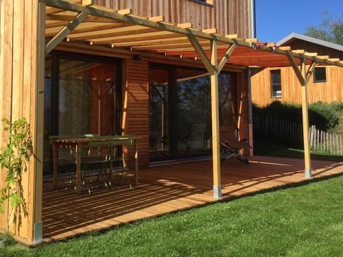 uma pérgola de madeira com uma mesa num deque em Gite Basse Correo em La Freissinouse