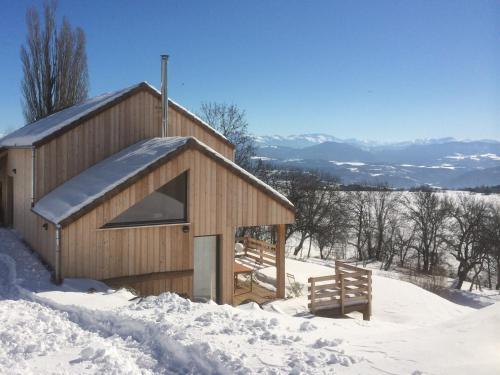 un petit bâtiment en bois dans la neige avec un banc dans l'établissement Gite Basse Correo, à La Freissinouse
