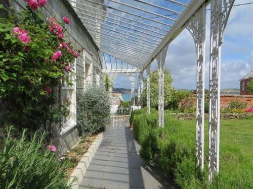 a greenhouse with a walkway in a garden with flowers at Coswarth House in Padstow