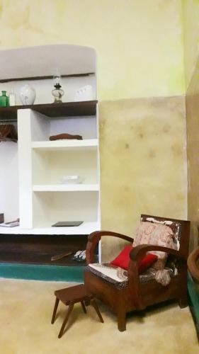 a living room with a chair in front of a bed at Jardim dos Aloés, Unique B&B - Casa de Charme in Ilha de Moçambique