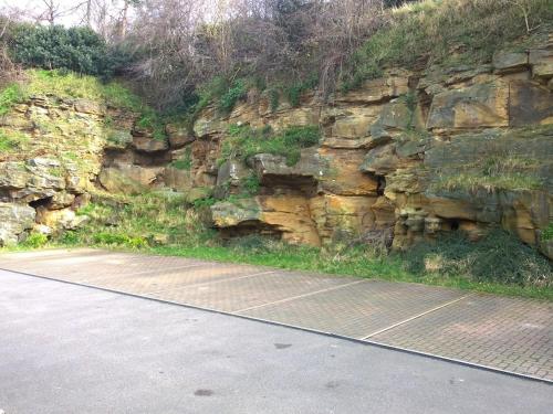 a stone wall next to a road next to a street at Your Travel Stop at Craggside in Woodhouse